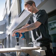 Wiertarko-wkrętarka Bosch GSR 18V-45 trzymana przez fachowca podczas precyzyjnego wkręcania wkrętów w drewnianą konstrukcję montażową.